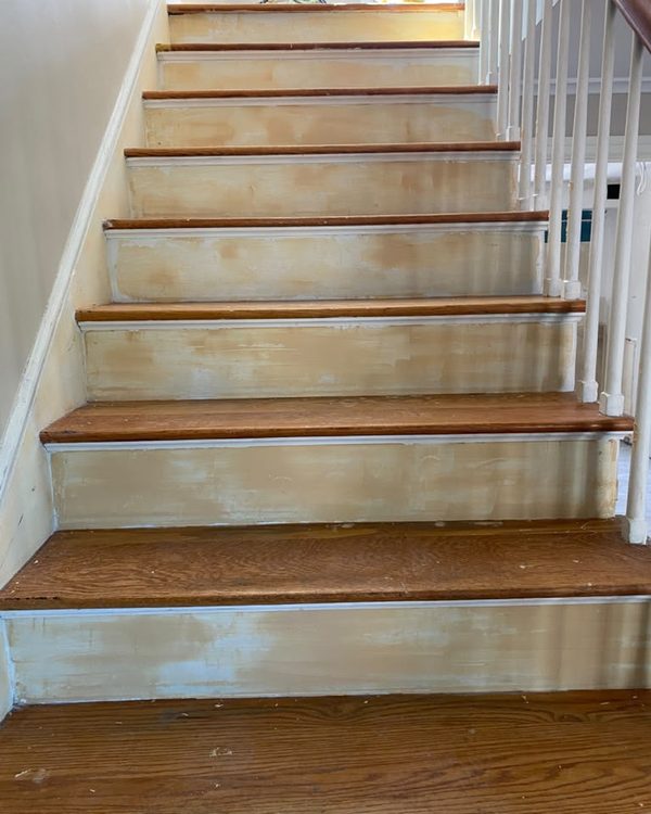 Before: Staircase risers sanded and patched before painting, with oak treads and white balusters