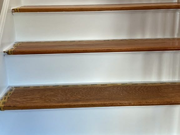Staircase with freshly painted white risers and taped oak treads