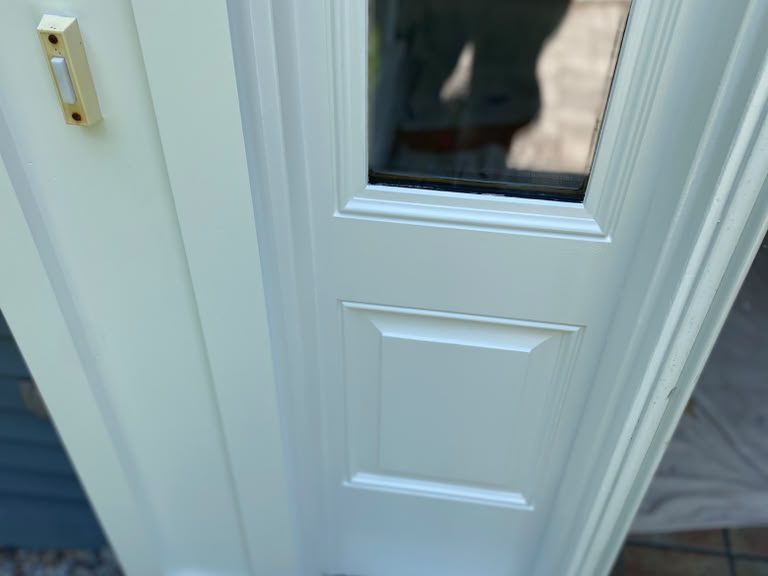 Entry door sidelight with fresh white paint and blue tape along the threshold