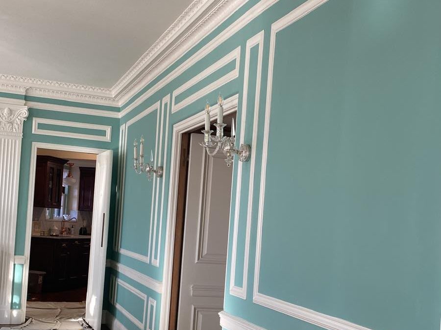 Formal room with turquoise walls, white crown and panel molding and crystal sconces