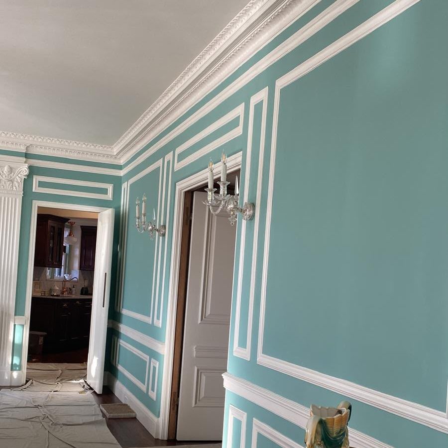 Formal room with turquoise walls, white crown and panel molding and crystal sconces