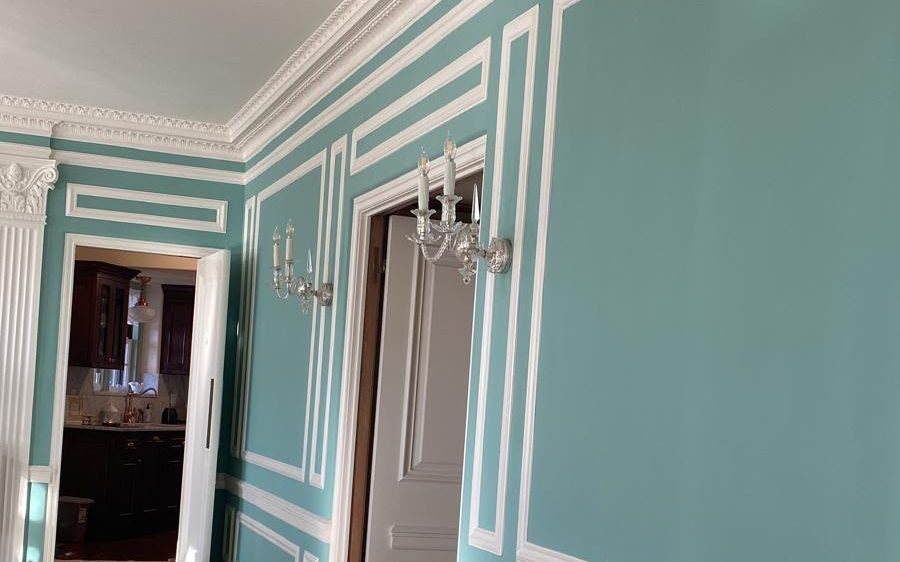 Formal room with turquoise walls, white crown and panel molding and crystal sconces