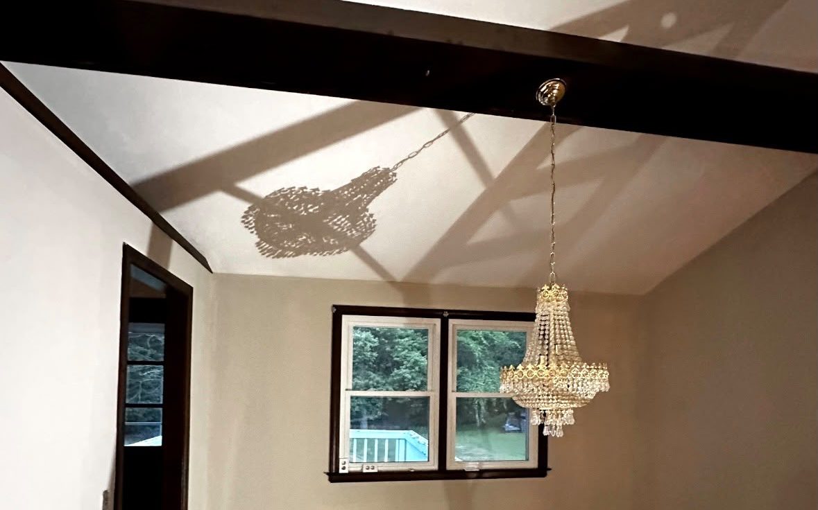 Living room with a vaulted white ceiling, dark beams, beige walls and a crystal chandelier
