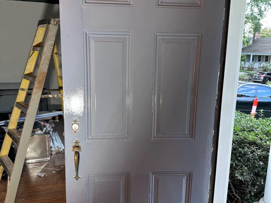 Six-panel front door freshly painted gray, standing open to the porch