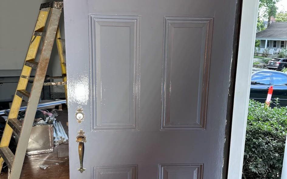 Six-panel front door freshly painted gray, standing open to the porch