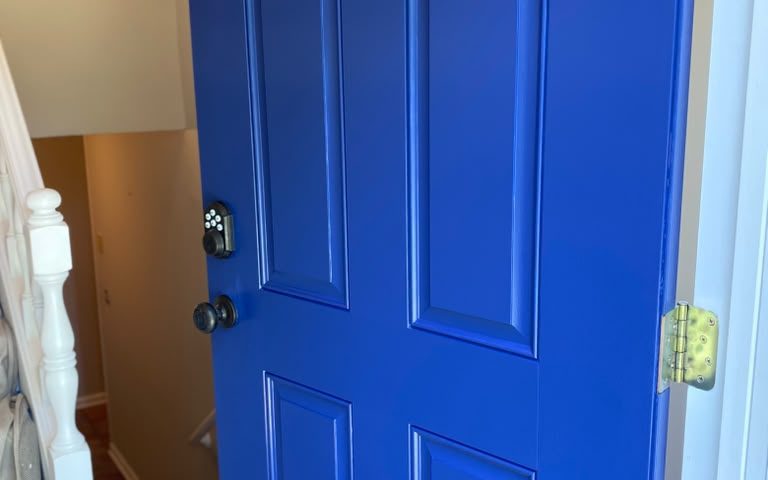 Six-panel interior door painted royal blue next to a staircase