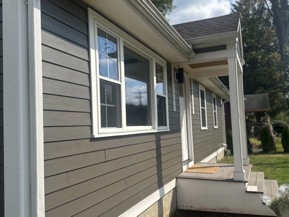 Side of a dark gray house with white window trim and porch columns
