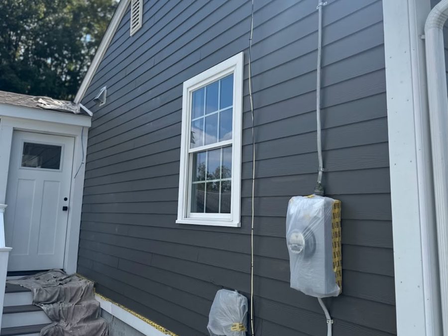 Gray house with the electric meter wrapped in plastic during painting