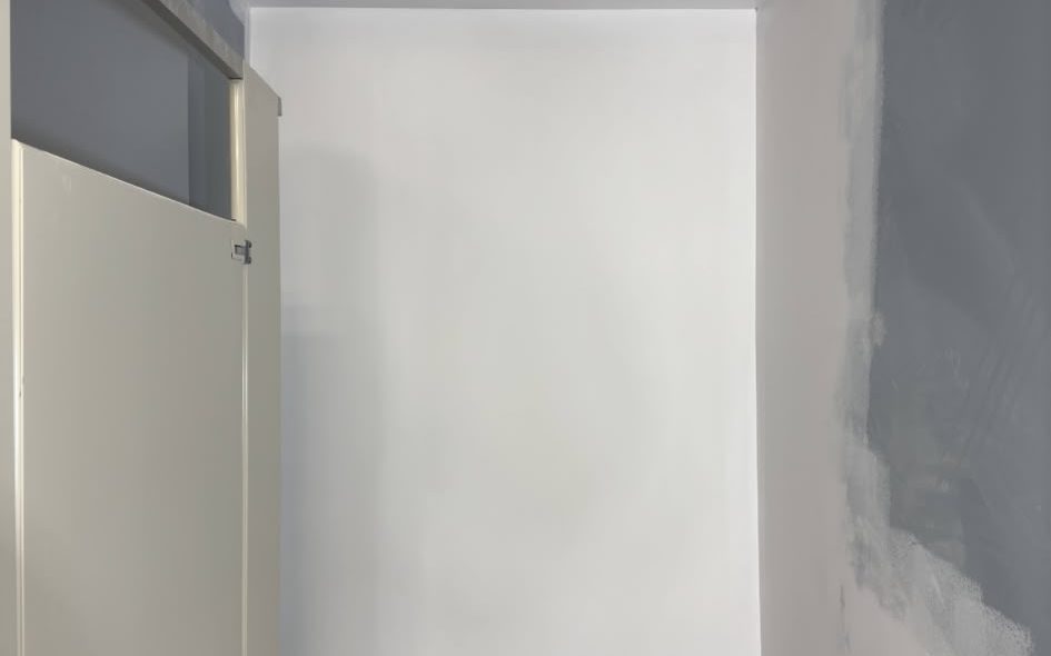 Commercial restroom wall repaired and primed, ready for finish coats