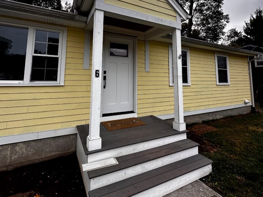 Yellow house with white trim, a small gabled porch and new gray steps