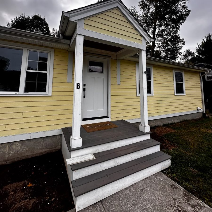 Yellow house with white trim, a small gabled porch and new gray steps