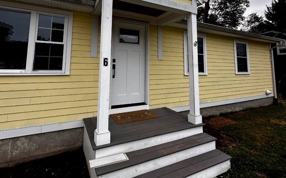 Yellow house with white trim, a small gabled porch and new gray steps