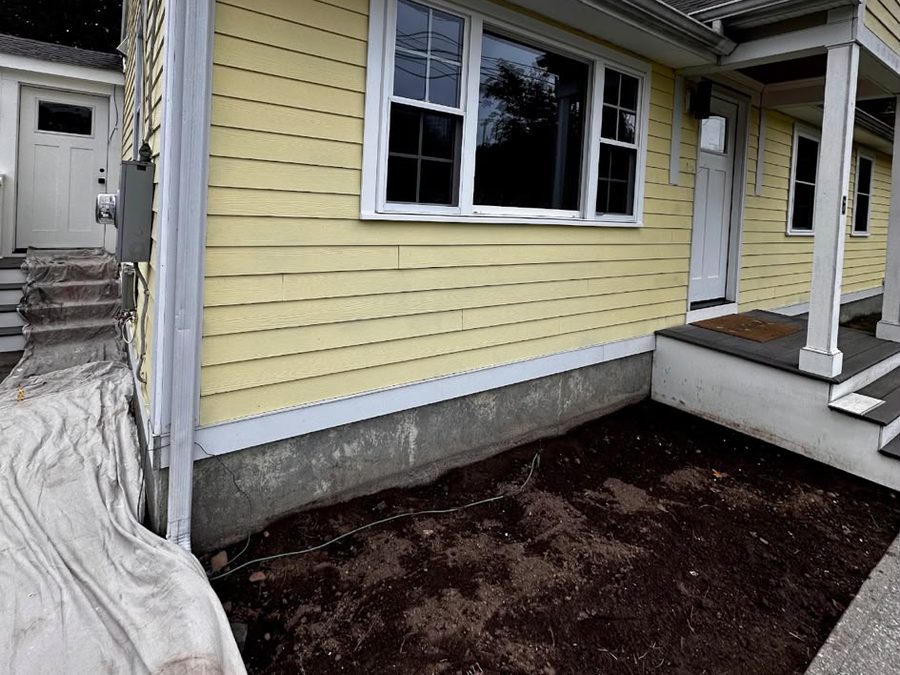 Side of a yellow house with drop cloths protecting the back steps