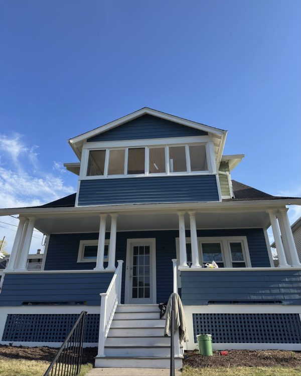 After: Two-story home painted blue with white columns, railings and lattice