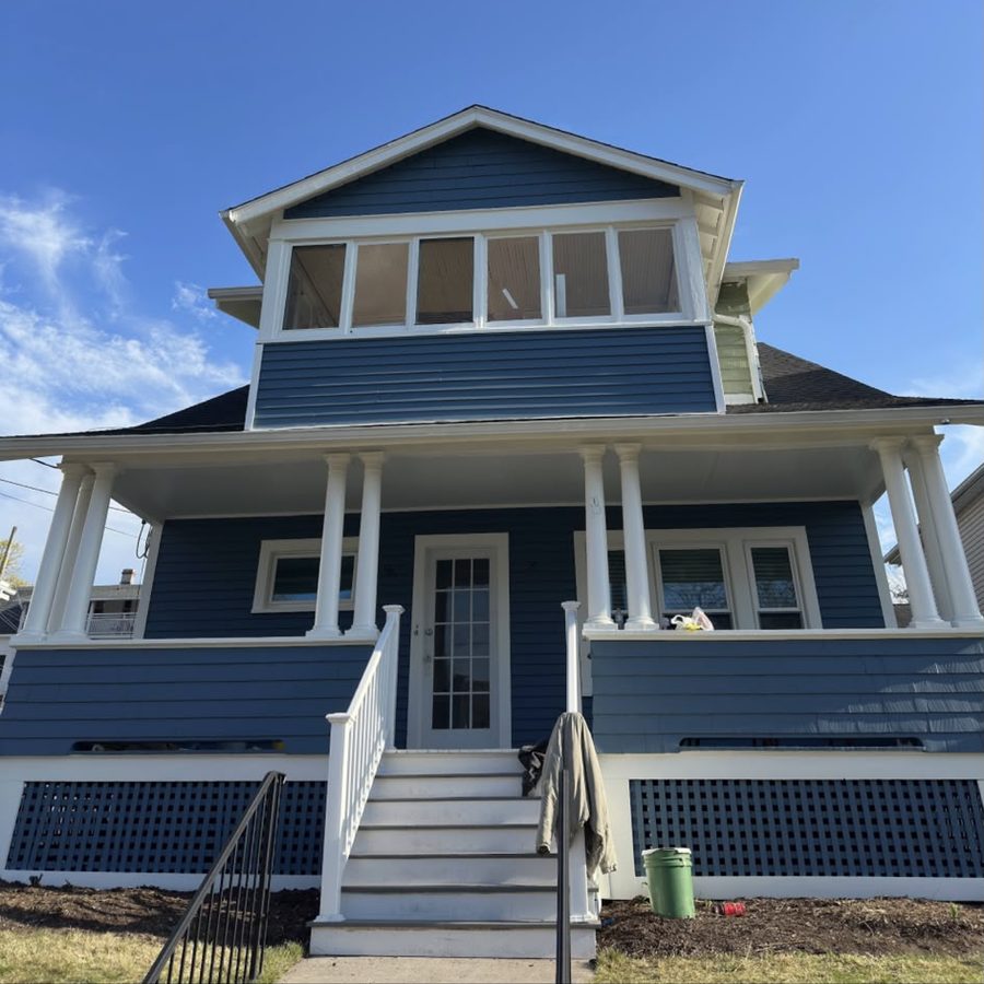 Two-story home painted blue with white columns, railings and lattice