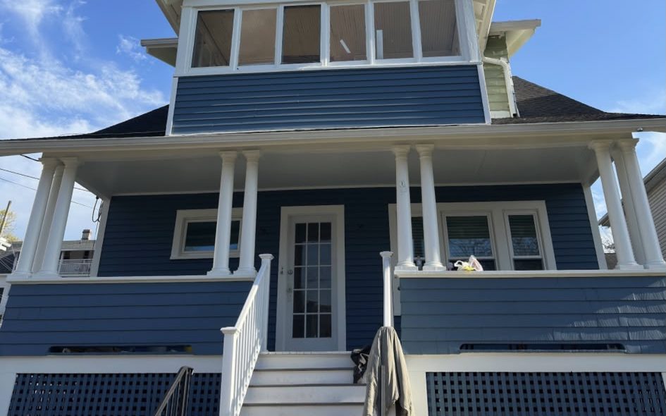 Two-story home painted blue with white columns, railings and lattice