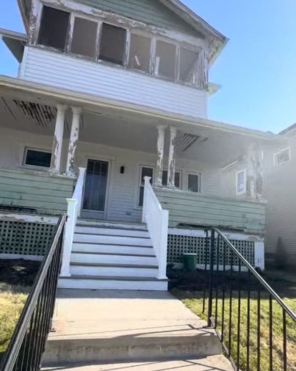 Before: Two-story home with peeling green and white paint on the porch and upper windows