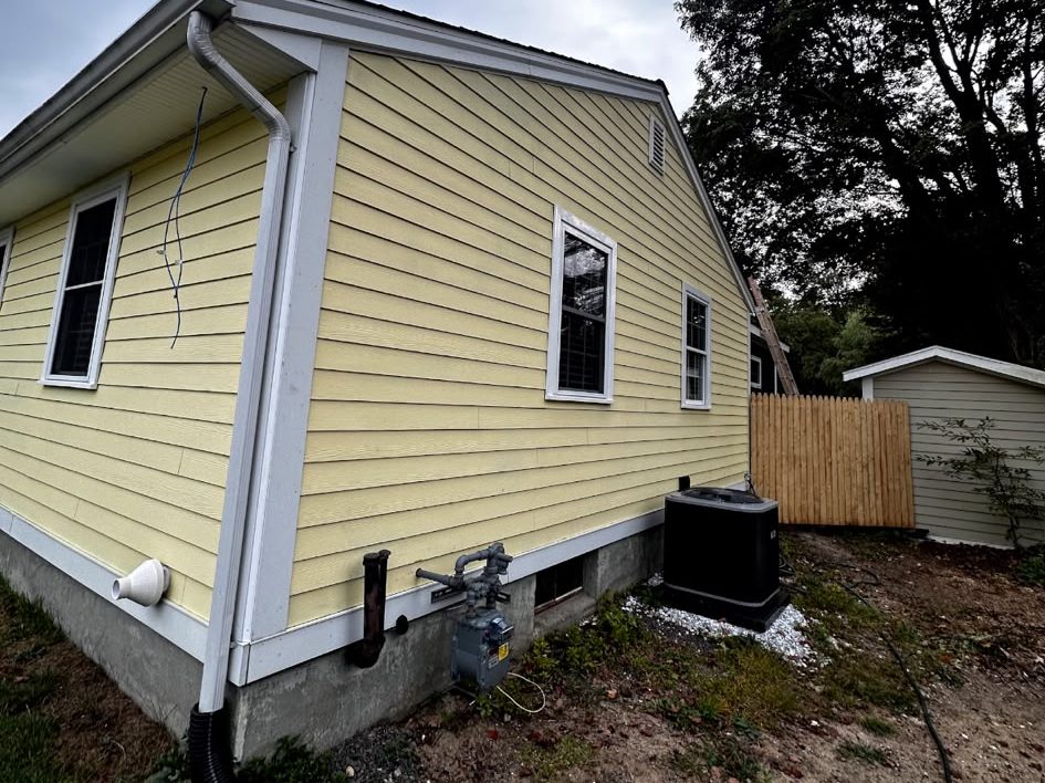 Back corner of a yellow house with white corner boards and trim