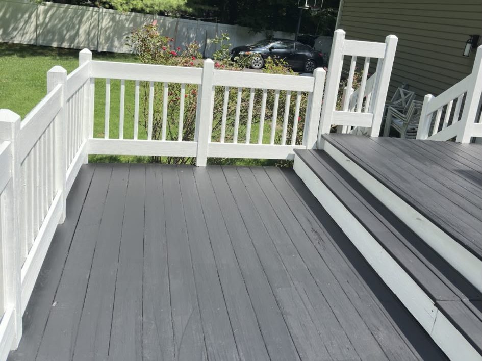 Charcoal deck with white railings and steps facing the backyard